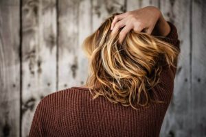 ragazza si gratta i capelli per cuoio capelluto irritato